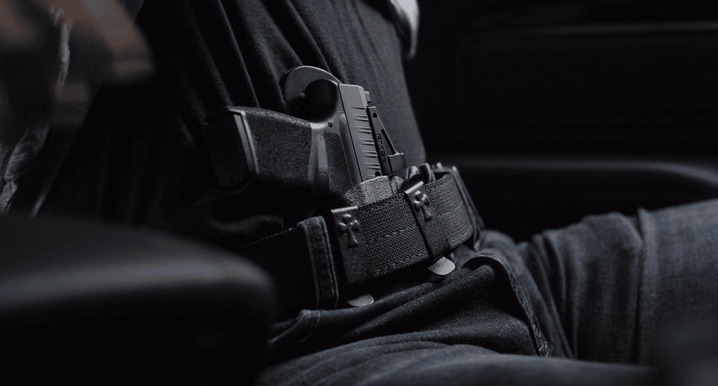 Close-up view of a handgun in a holster attached to a person's belt.